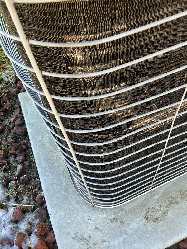 # HVAC Maintenance - Cooling

Completed scheduled maintenance on a 22-year-old air conditioning system. Upon inspection, the outdoor condenser unit showed significant dirt and debris accumulation on the coil fins, with visible brownish discoloration and streaking indicating restricted airflow. The evaporator coil assembly also exhibited yellowish-tan deposits concentrated in the center-right section of the fin assembly, consistent with dust and environmental buildup affecting heat transfer efficiency.

Performed comprehensive cleaning of both the condenser and evaporator coils to remove accumulated debris and restore proper airflow through the fin assemblies. Straightened bent fins where necessary to maximize surface area contact. Inspected all refrigerant lines and connections for signs of wear or leakage. Verified proper operation of the protective wire guard surrounding the condenser unit. Checked concrete pad for levelness and stability. 

System tested and confirmed operational fo