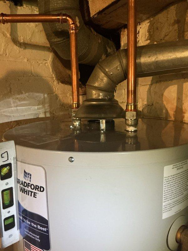 Replaced existing 40-gallon standard atmospheric vent water heater with new Bradford White unit in basement location. Installation included proper leveling of unit on concrete floor, connection of copper supply lines with brass fittings and compression joints, and attachment to existing gray metal vent piping for exhaust ventilation. Verified unit was plumb and level to manufacturer specifications to ensure proper operation and longevity of the appliance.