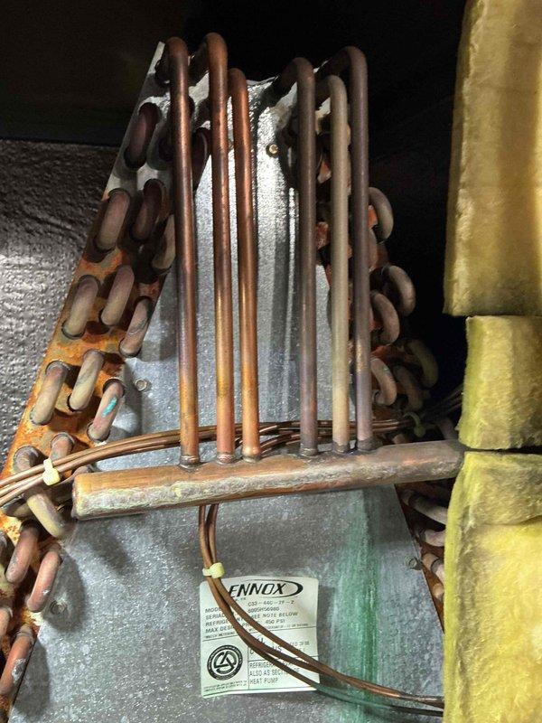 Completed annual air conditioning tune-up on 20-year-old Lennox system. Inspected evaporator coil assembly, verified refrigerant line connections, and documented condition of unit showing age-appropriate wear with minor oxidation on copper lines and rust staining on plenum housing. System operational and ready for cooling season.