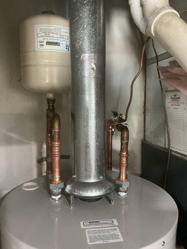 Responded to service call for leaking water heater with no hot water production. Upon arrival, inspected Bradford White 40-gallon natural gas water heater model RG240T6N. Confirmed active leak and lack of hot water delivery to fixtures. Given the age uncertainty of the unit and homeowner's recent property purchase, assessed overall condition of water heater and surrounding plumbing connections. Documented existing installation including copper supply lines with dielectric unions, galvanized vent flue, and expansion tank configuration. Verified proper venting and gas connections. Provided customer with assessment findings and recommended solutions for restoring hot water service to the residence.