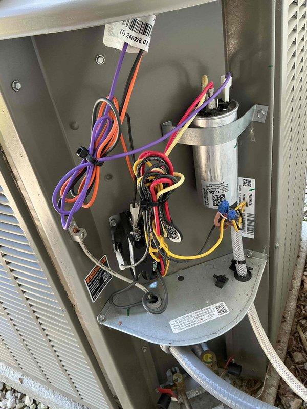 Responded to service call for unusual noise during AC operation. Performed diagnostic inspection of outdoor condenser unit and internal components. Removed access panel and inspected electrical connections, capacitor, and wiring harness - all found to be secure and properly routed. Verified condenser unit exterior condition, fan operation, and refrigerant line connections. Unit operating within normal parameters at time of inspection.
