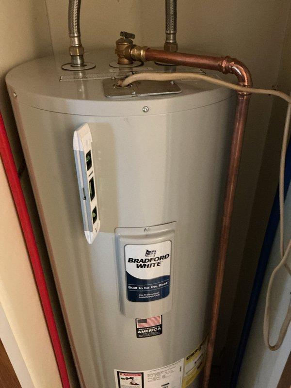 Completed installation of a 50-gallon Bradford White electric water heater in an under-counter cabinet space. Connected hot and cold water supply lines using flexible braided stainless steel connectors with shut-off valves, installed temperature and pressure relief valve with discharge piping, and verified all plumbing connections for proper operation and leak-free performance.