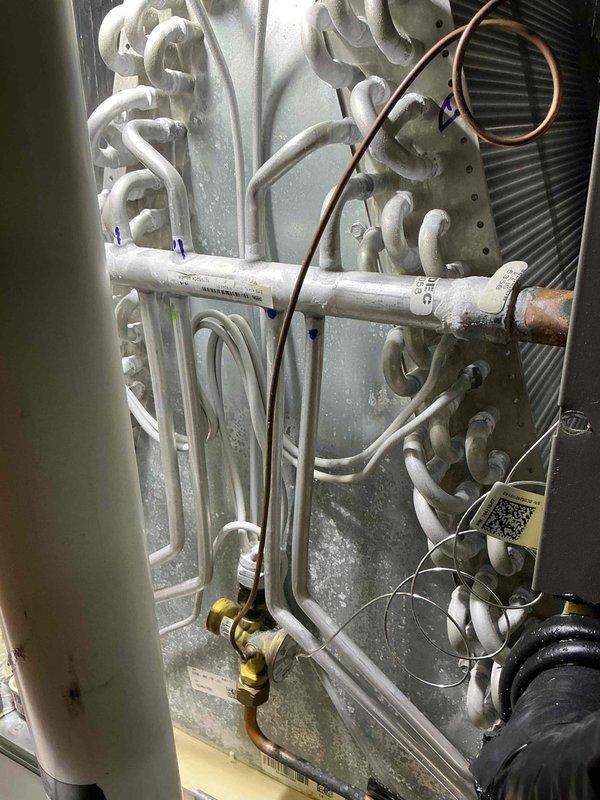 Responded to cooling system malfunction on a 2-year-old air conditioning unit during scheduled recurring maintenance visit. Upon inspection, discovered extensive ice and frost buildup on the evaporator coil assembly, with crystalline accumulation covering the copper refrigerant lines and metallic surfaces. The heavy frost formation indicated abnormal system operation requiring immediate attention.

Performed diagnostic assessment of the frozen evaporator coil condition. Utilized borescope inspection camera to examine ductwork and confined spaces for potential airflow restrictions or insulation issues that could contribute to the freezing condition. Documented system conditions with photographic evidence showing the severity of ice accumulation on the coil assembly, refrigerant lines, and heat exchanger components.

Addressed the underlying cause of the freeze-up condition, which typically results from restricted airflow, low refrigerant charge, or improper system operation. Allowed ade