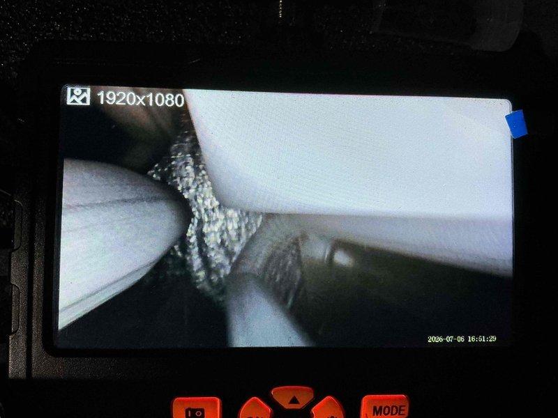 Responded to no-cooling complaint on central air conditioning system. Upon arrival, confirmed unit running continuously with airflow present but inadequate cooling performance. Customer reported filter replacement prior to service call with no improvement. Performed visual inspection of outdoor unit and refrigerant lines with no visible frost or condensation abnormalities noted.

Conducted internal system inspection using borescope camera to assess evaporator coil condition within air handler. Documentation revealed evaporator coil fins with visible contamination and restricted airflow capacity. Images captured show significant debris accumulation between aluminum fins, consistent with lack of preventative maintenance since 2018. The reduced heat transfer efficiency from dirty coil explains continuous runtime without achieving temperature setpoint.

Recommended thorough evaporator coil cleaning and complete system maintenance to restore proper cooling capacity and efficiency.