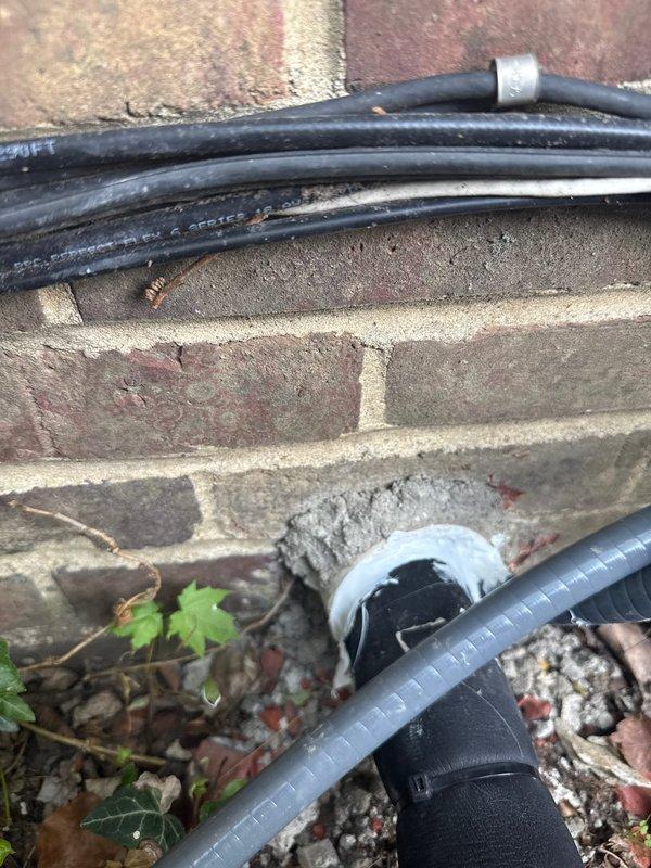 Performed warranty inspection correction on exterior HVAC line set installation. The original PVC sleeve penetration through the building envelope had not been properly sealed with silicone, allowing potential air and moisture infiltration. Accessed the exterior line set location where refrigerant lines exit the structure through the foundation area. Removed inadequate existing sealant and thoroughly cleaned the PVC sleeve and surrounding penetration area. Applied proper silicone sealant around the line set where it passes through the PVC sleeve, ensuring complete weather-tight seal between the conduit and building exterior. Verified proper sealing of all gaps to prevent water intrusion, pest entry, and air leakage. Additionally inspected the condition of line set insulation along the exterior run and documented areas where foam insulation had deteriorated or separated from the refrigerant lines. Photographed the installation for warranty documentation purposes. Work completed from bui