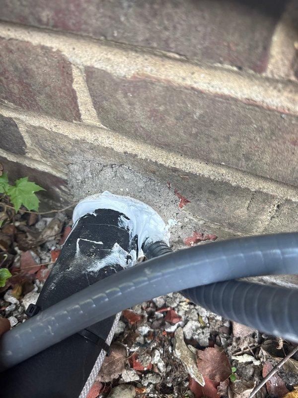 Performed warranty inspection correction on exterior HVAC line set installation. The original PVC sleeve penetration through the building envelope had not been properly sealed with silicone, allowing potential air and moisture infiltration. Accessed the exterior line set location where refrigerant lines exit the structure through the foundation area. Removed inadequate existing sealant and thoroughly cleaned the PVC sleeve and surrounding penetration area. Applied proper silicone sealant around the line set where it passes through the PVC sleeve, ensuring complete weather-tight seal between the conduit and building exterior. Verified proper sealing of all gaps to prevent water intrusion, pest entry, and air leakage. Additionally inspected the condition of line set insulation along the exterior run and documented areas where foam insulation had deteriorated or separated from the refrigerant lines. Photographed the installation for warranty documentation purposes. Work completed from bui