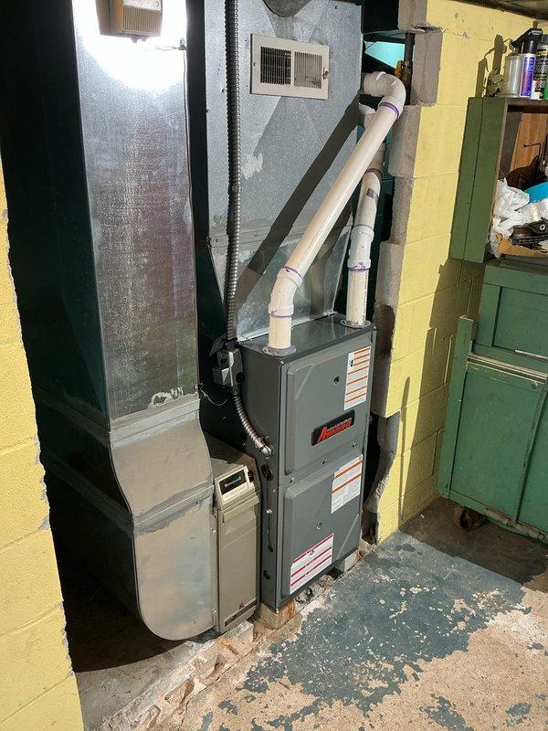 Completed installation of Amana replacement furnace in residential basement utility space. System includes proper PVC venting configuration for intake and exhaust, with all ductwork connections secured and operational. Unit tested and verified for safe operation with all warning labels visible and accessible per manufacturer specifications.