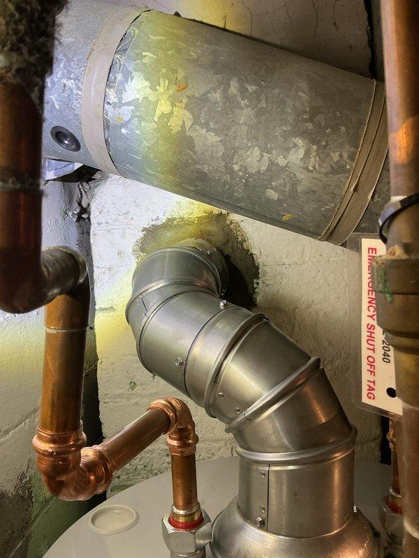 Replaced aging 40-gallon natural gas water heater in basement utility room of residential property built in 1928. Removed deteriorated existing unit showing significant corrosion and exterior degradation, then installed new white tank water heater with proper copper piping connections, temperature and pressure relief valve, and code-compliant venting. All plumbing connections secured with appropriate fittings, gas line reconnected, and unit tested for proper operation and safety compliance.