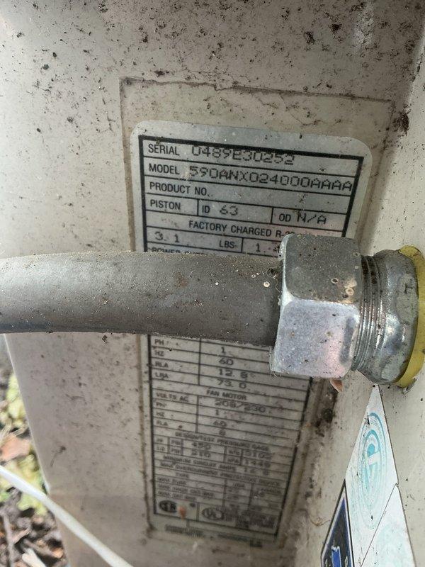 # No Cool Service Call

Responded to a no cooling complaint on a residential air conditioning system. Upon arrival, performed system diagnostics and visual inspection of outdoor condensing unit. Unit identified as Goodman model 5504MX024000PAAP with serial number U488990432. 

Inspected refrigerant lines, filter drier, and compressor connections at outdoor unit. Observed typical wear and environmental exposure on equipment exterior with accumulated dirt and debris on components and surrounding concrete pad. Verified proper electrical connections and examined refrigerant line routing along building exterior. System components including blue filter drier and copper refrigerant lines inspected for leaks, damage, or restrictions.

Documented equipment condition with photographs showing nameplate data, piping configuration, and component layout. Unit factory charged with refrigerant per specifications on data plate showing piston ID 63 and OD 117.8 measurements. All findings and system info