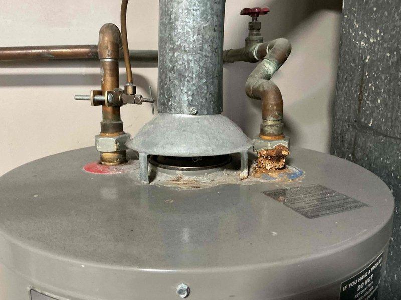 Responded to no cooling call on 25+ year old air conditioning system. Upon arrival, conducted diagnostic inspection of HVAC equipment. Documentation photos captured water heater and associated plumbing components in mechanical room, showing aged copper piping, corrosion buildup, and galvanized ductwork, though primary service focus was air conditioning system evaluation for the non-functional cooling unit.