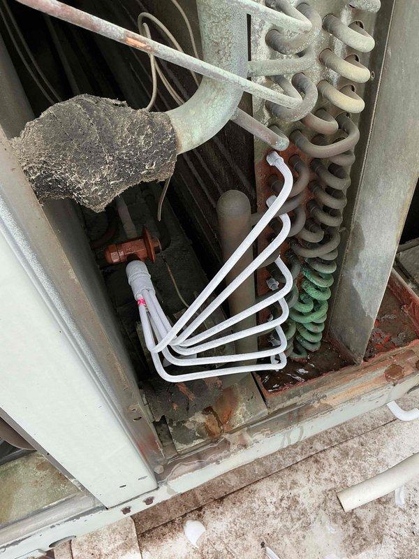 # Commercial Rooftop AC Unit - No Cooling Complaint

Responded to no cooling complaint on commercial rooftop air conditioning unit. Upon arrival, accessed unit via side entrance as instructed and proceeded to rooftop for diagnostic evaluation.

## Inspection Findings

Conducted thorough visual inspection of rooftop unit interior components. Found evaporator coil exhibiting severe corrosion and oxidation throughout its serpentine structure. Coil displayed progressive deterioration with white oxidation on upper sections, rust-colored corrosion in middle portions, and green-blue copper patina on lower coils, indicating prolonged moisture exposure and chemical degradation.

Observed substantial dirt and debris accumulation throughout unit cabinet, particularly at base and on mechanical components. Blower assembly showed heavy dust and lint buildup on motor and housing. Interior surfaces displayed rust staining and general deterioration consistent with extended service life in harsh environ