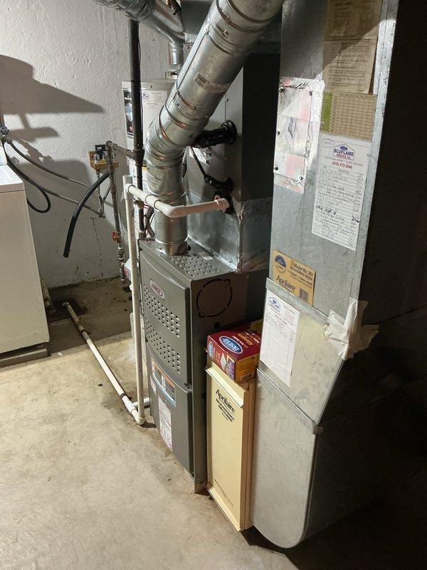 Responded to installation callback to address venting code compliance issues. Corrected hot water tank vent configuration to enter chimney higher than furnace vent per code requirements and adjusted pitch on water heater venting that had been altered during original furnace installation. Verified proper slope using level to ensure condensate drainage. Installed surge protector for equipment protection and provided thermostat programming assistance to ensure proper system operation.