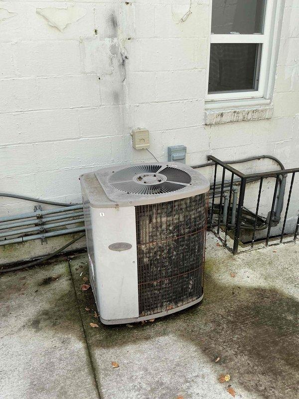 Responded to no cooling complaint on residential air conditioning system. Upon arrival, confirmed outdoor fan motor operation but system failing to produce cool air. Performed diagnostic inspection of outdoor condenser unit, which exhibited significant weathering, dirt accumulation, and rust staining on exterior surfaces. Visual inspection revealed deteriorated insulation on refrigerant line set and general lack of maintenance. System evaluation confirmed customer suspicion of refrigerant loss, likely due to leak in refrigerant circuit. Documented equipment condition with photos showing heavily soiled condenser coil and degraded components requiring attention.