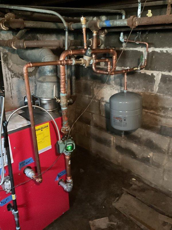Responded to service call for boiler system evaluation. Upon arrival, assessed existing boiler installation that was previously completed by another contractor. Inspection revealed the system was not installed properly according to code requirements. Documented extensive copper piping configuration, expansion tank mounting, and red boiler unit connections with pressure gauges and valving system. Coordinated scheduling availability and provided estimate for proper reinstallation work. Customer acknowledged that permit will be required for corrective installation to bring system into compliance with local building codes and manufacturer specifications.