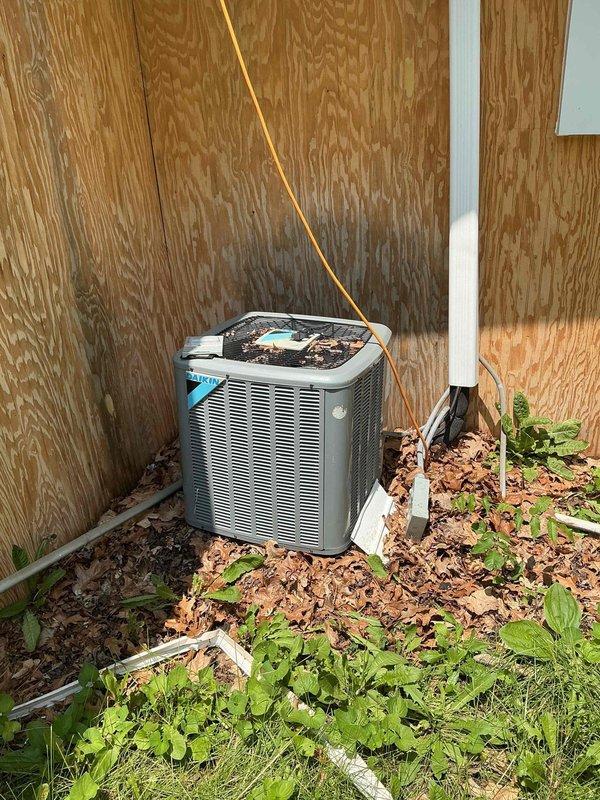 # HVAC Service Call - No Cooling Issue

Responded to service call for 10-year-old residential air conditioning system that failed to turn on. Upon arrival, performed visual inspection of outdoor condenser unit located against exterior building wall. Unit showed signs of neglect with significant leaf litter and organic debris accumulation around base and heavy vegetation growth obstructing airflow to lower intake areas.

Verified electrical disconnect box present at unit location. Traced copper refrigerant lines and electrical conduit connections from unit to building. Checked power supply at disconnect and confirmed electrical connection integrity. Cleared debris field surrounding condenser unit to restore proper airflow clearance and prevent future operational issues.

Performed system startup sequence and verified compressor engagement. Tested contactor operation and confirmed proper voltage delivery to unit components. System restored to operational status with cooling functionality