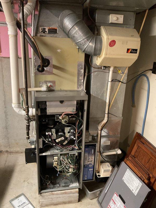 Conducted comprehensive assessment of existing HVAC system for complete furnace and air conditioning replacement. Evaluated current outdoor condensing unit mounted on exterior foundation alongside electrical meter and service disconnect, noting equipment age and operational condition. Inspected indoor furnace installation in mechanical room, including existing ductwork configuration, humidifier integration, electrical panel connections, and PVC condensate drainage system. Documented equipment specifications, clearances, and utility connections to provide accurate replacement estimate for new heating and cooling system.