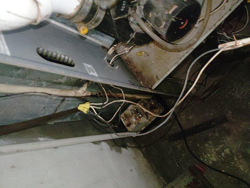 Responded to service call for two non-operational air conditioning units following a power surge. Upon inspection, confirmed electrical damage to control boards on both systems, with visible signs of power surge impact including compromised wiring connections and corroded electrical components. Assessed extensive deterioration throughout both units, including significant rust on metal components, mold growth on surfaces, and moisture damage indicating prolonged exposure and deferred maintenance. Documented electrical connection points showing yellow wire connectors at junction areas, corroded metal brackets, and compromised housing panels. Verified electrician's preliminary assessment and provided professional HVAC evaluation confirming control board failure on both units requiring replacement to restore operation.
