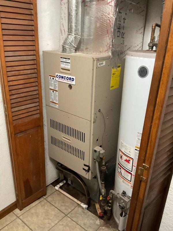 Completed comprehensive estimate for full HVAC system replacement at residential property. Assessed existing Concord furnace unit located in interior utility closet with flexible metallic ductwork and outdoor cylindrical air conditioning condenser unit positioned against exterior wall. Documented current equipment configuration including gas connections, water heater proximity, ductwork transitions, and condenser placement on grade with nearby landscaping. Provided detailed replacement specifications and equipment recommendations for complete heating and cooling system upgrade.