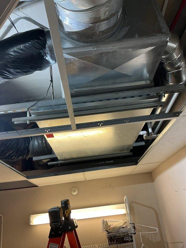 Completed full HVAC system installation including AHRI-matched air handler with electric heat strips mounted in drop ceiling with custom metal return and supply plenums for optimal airflow. Installed new condensate drain pan with flood control device and PVC drainage system, added return ductwork to back hallway using 8" flex duct terminated with bar-face filter grill, and flushed existing line set for reuse. Positioned heat pump condenser on roof-mounted pad with Unistrut support structure for electrical disconnect, installed new disconnect box with whip, and wired WiFi-enabled smart thermostat for remote system control. All equipment commissioned and tested for proper operation with 10-year parts and labor warranty coverage.