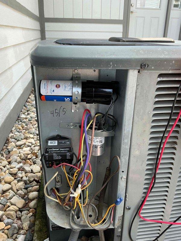 Responded to no cooling complaint on 10-year-old residential air conditioning system. Upon arrival, verified outdoor condenser unit was running but system was not producing cold air. Removed access panel and inspected electrical components including dual-run capacitor (46/5 MFD) and CoreSense diagnostic module. Diagnosed failed capacitor causing compressor to fail to start properly, resulting in loss of cooling capacity. Replaced defective capacitor with OEM-equivalent part, tested system operation, and confirmed proper amperage draw and cooling performance restored.
