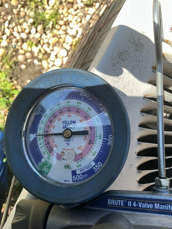 Responded to no cooling complaint with recurring frozen refrigerant line on aging system. Upon arrival, found evaporator coil had previously frozen and thawed. Attached manifold gauges to outdoor condensing unit to check system pressures and diagnose root cause of repeated freeze-ups. System pressures indicated low refrigerant charge, which restricts proper heat exchange and causes ice formation on suction line and evaporator coil. Recommended addressing refrigerant leak and recharge to restore proper cooling operation and prevent continued freeze-up cycles.
