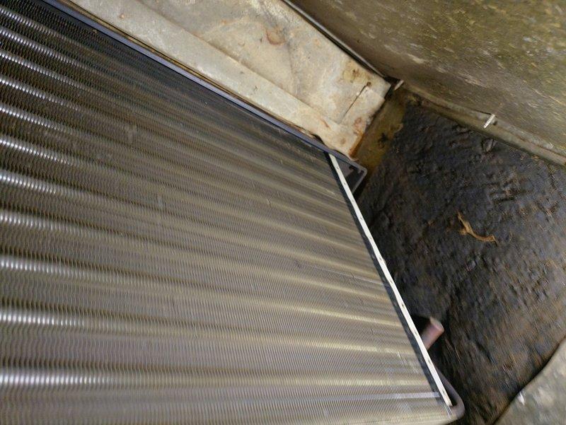 Responded to service call for air conditioning unit not cooling properly and experiencing freeze-up conditions. Upon inspection, discovered 15-year-old furnace system with evaporator coil showing signs of restricted airflow due to contamination. Found significant mold and debris accumulation on surrounding surfaces and ductwork, along with corroded refrigerant line connections exhibiting rust and mineral deposits. The evaporator coil's aluminum fins were compromised by poor air quality and lack of maintenance in the mechanical space. Documented existing conditions including deteriorated insulation, biological growth on wooden surfaces, and aged ductwork with discoloration indicating moisture exposure. Advised customer of findings and provided recommendations for system cleaning, possible coil replacement, and addressing underlying moisture issues to prevent future freeze-up conditions and restore proper cooling operation.