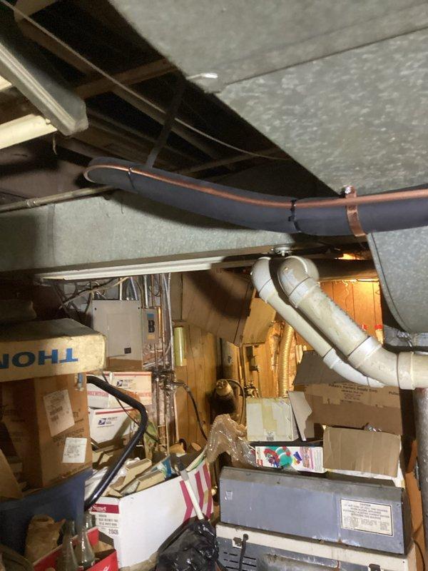 Completed retrofit installation of air conditioning system with evaporator coil on existing furnace in basement utility area. Installed 20" coil to accommodate spatial constraints, ran new 3/4" x 40' refrigerant line set, and positioned outdoor unit on new equipment pad with disconnect and whip. Installed dedicated electrical circuit using approximately 40' of #10 AWG wiring to meet code requirements, relocated two mini-split units to create adequate clearance for new equipment, and mounted new programmable thermostat for system control.