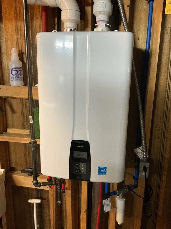 Completed professional installation of a wall-mounted Navien tankless water heater in utility area with exposed stud framing. Mounted unit securely to wall structure and established all necessary connections including hot and cold water supply lines with color-coded piping (red for hot, blue for cold), PVC venting system routed through top of unit, gas supply line with appropriate shut-off valves, and electrical connections via flexible metal conduit. Installed isolation valves on both water supply lines for future maintenance access and incorporated sediment filter on cold water inlet to protect unit from debris. Completed all venting requirements per manufacturer specifications using white PVC pipe. Verified proper operation of digital control panel and tested unit for leaks at all connection points. Installation meets current plumbing codes and Energy Star efficiency standards.