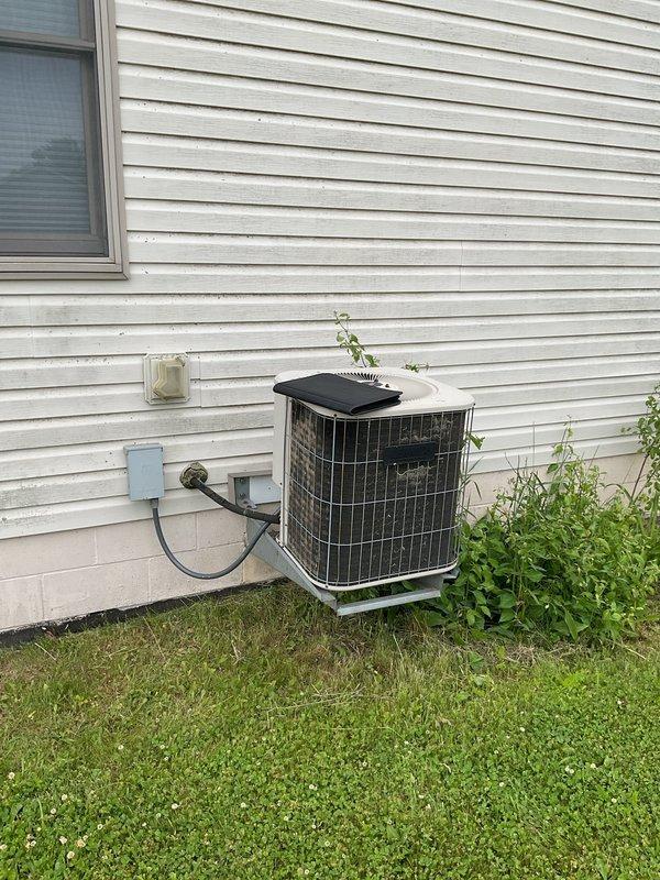 Conducted comprehensive assessment of existing HVAC system for complete replacement estimate. Evaluated outdoor condensing unit positioned on concrete pad with electrical disconnect, noting weathered condition and vegetation encroachment affecting clearances. Inspected basement furnace installation including Lennox gas furnace with overhead ductwork configuration and adjacent water heater. Documented current equipment specifications, electrical connections, duct routing, and installation conditions to provide accurate replacement recommendations for both heating and cooling systems.
