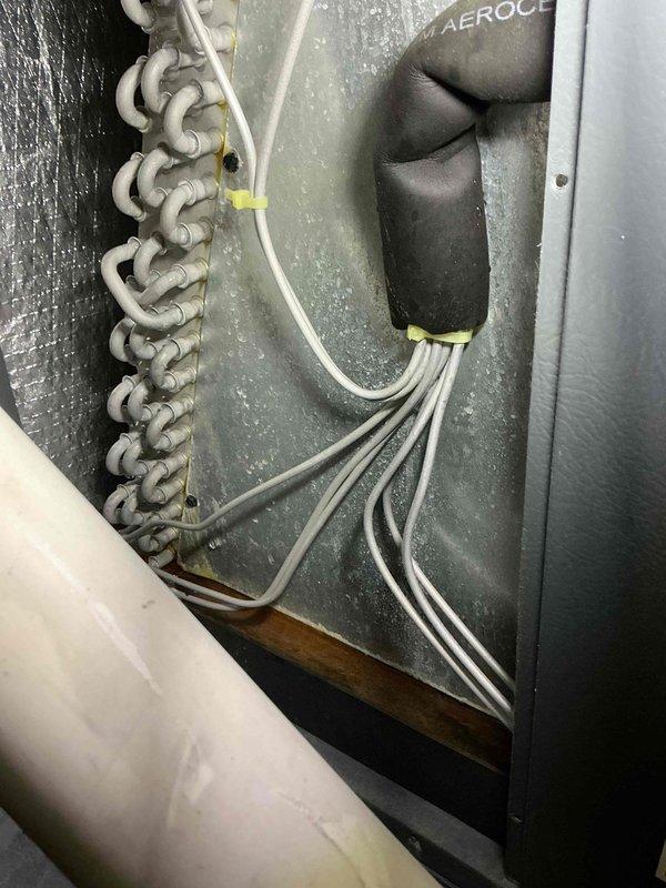 Completed scheduled cooling maintenance on residential air handler system. Performed inspection of evaporator coil using borescope camera to assess internal fin condition and checked refrigerant line connections. Documented equipment condition with photos showing U-bend copper coil configuration and insulated refrigerant lines in attic installation.