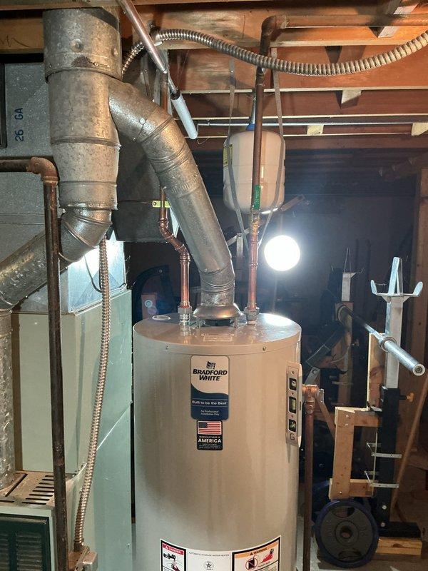 Conducted on-site assessment of non-functional Bradford White water heater in residential basement utility room of 1970s-era home. Documented existing installation configuration including copper supply piping, gas line connections, flexible metal conduit, exhaust venting with angled elbow assembly, and shut-off valve locations. Evaluated equipment condition, surrounding mechanical room layout with adjacent HVAC system, and existing plumbing infrastructure to provide comprehensive replacement quote for professional water heater installation.