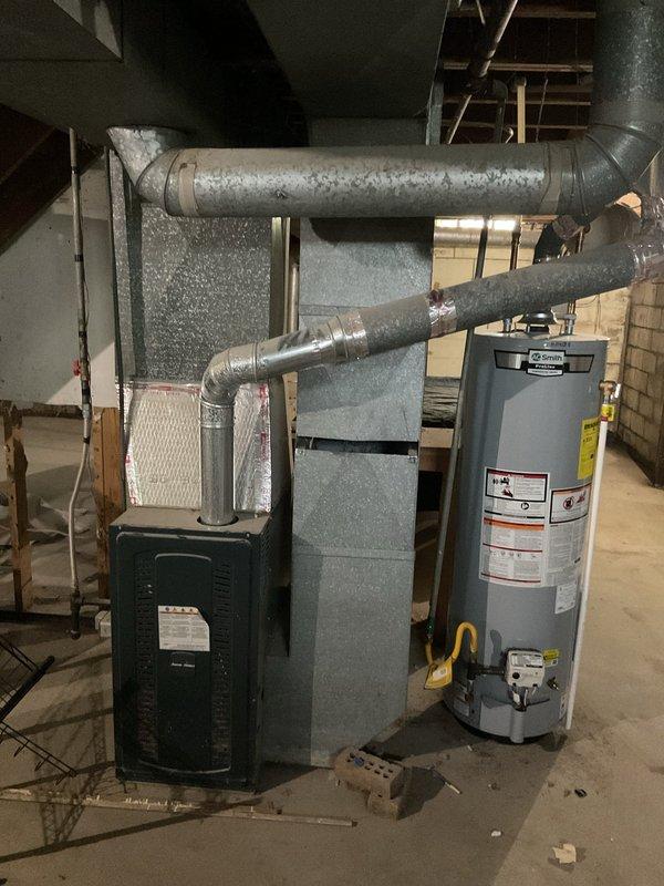 Conducted comprehensive assessment of existing HVAC system for complete replacement estimate. Evaluated current furnace unit and air conditioning system, documenting equipment age, condition, and installation configuration. Inspected exterior condenser location and clearances near foundation landscaping area, noting available space for new equipment placement. Assessed interior installation including existing ductwork connections, venting arrangement, and spatial requirements in basement utility area. Documented current system specifications and measured dimensions for proper equipment sizing recommendations. Provided detailed replacement options for both heating and cooling components based on home's requirements and existing infrastructure.