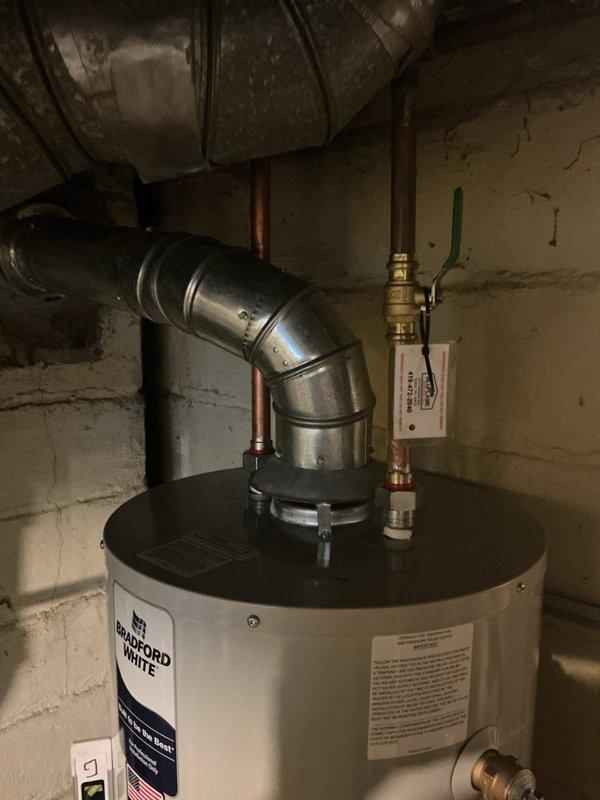 Responded to service call for water heater estimate. Upon arrival, assessed existing Bradford White tanked water heater installation in basement utility area. Inspected unit condition, venting system with metallic ductwork, copper supply line connections, brass shutoff valve, and pressure relief valve assembly. Photographed current installation showing unit positioned against concrete block wall with all plumbing connections and electrical wiring visible. Provided customer with replacement estimate options and discussed available water heater models meeting their needs.