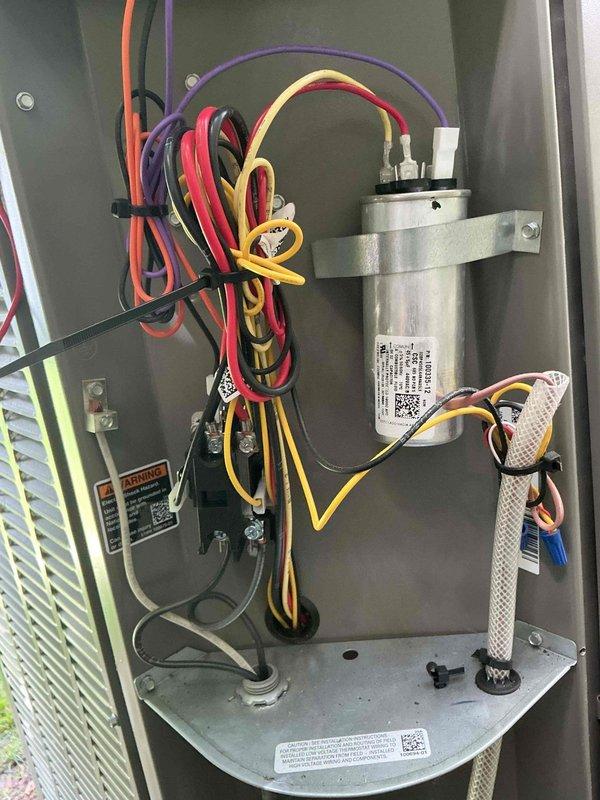Completed annual preventive maintenance on a one-year-old residential air conditioning system. Inspected electrical components, capacitor, and wiring connections within the outdoor condensing unit, verified all connections were secure and properly terminated. Confirmed system monitoring device was operational with active status indicator and properly mounted to supply ductwork with all communication cables connected.