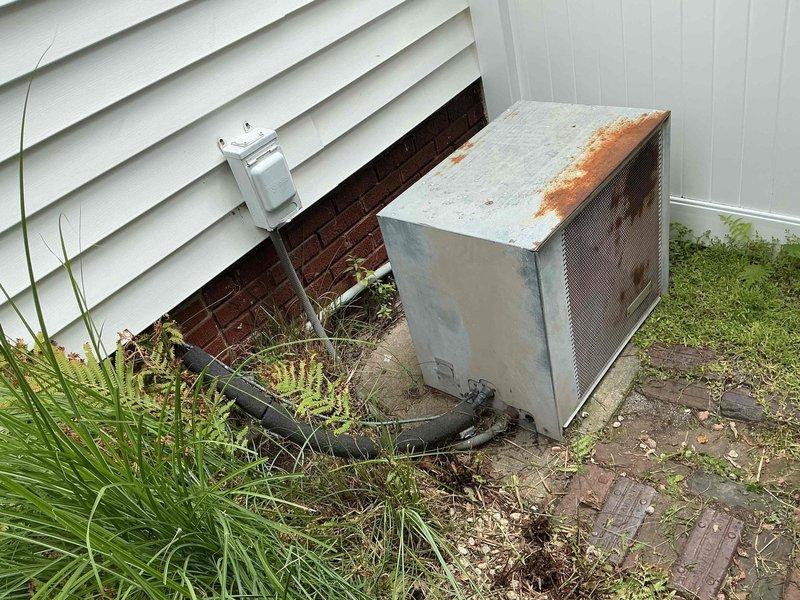 # HVAC Service Call - No Cooling Complaint

Responded to service call for 25-year-old residential air conditioning system blowing warm air. Upon arrival, performed visual inspection of outdoor condensing unit, which showed significant age-related deterioration including substantial rust on top panel and weathered cabinet finish. Unit was accessible on ground-level installation with vegetation growth around perimeter.

Conducted diagnostic evaluation of system performance and refrigerant charge levels. Testing confirmed low refrigerant condition causing loss of cooling capacity. Set up manifold gauges and service equipment to assess system pressures and identify refrigerant requirements.

Based on system age and observed conditions, provided customer with assessment of current system status. Unit is operating beyond typical service life expectancy for residential HVAC equipment. Discussed repair options versus replacement considerations given the advanced age of the equipment and potent