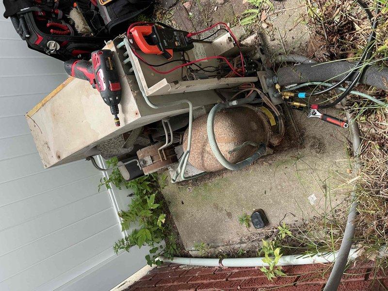 # HVAC Service Call - No Cooling Complaint

Responded to service call for 25-year-old residential air conditioning system blowing warm air. Upon arrival, performed visual inspection of outdoor condensing unit, which showed significant age-related deterioration including substantial rust on top panel and weathered cabinet finish. Unit was accessible on ground-level installation with vegetation growth around perimeter.

Conducted diagnostic evaluation of system performance and refrigerant charge levels. Testing confirmed low refrigerant condition causing loss of cooling capacity. Set up manifold gauges and service equipment to assess system pressures and identify refrigerant requirements.

Based on system age and observed conditions, provided customer with assessment of current system status. Unit is operating beyond typical service life expectancy for residential HVAC equipment. Discussed repair options versus replacement considerations given the advanced age of the equipment and potent