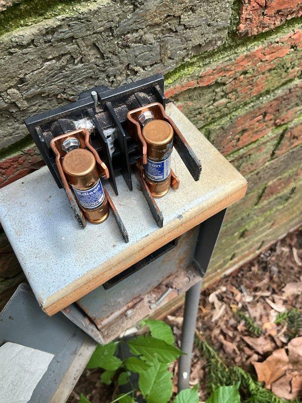 Completed preventive maintenance on a 4-year-old air conditioning system. Inspected electrical disconnect and fuse assembly, verified proper connections, and documented equipment condition with photos showing outdoor components including weathered disconnect box and exterior-mounted electrical housing with conduit.