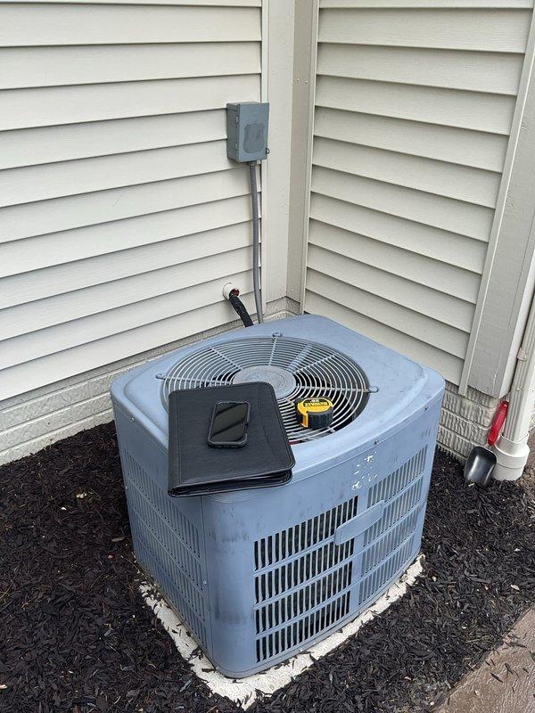 Completed comprehensive estimate for full HVAC system replacement including outdoor condensing unit and indoor furnace. Evaluated existing light blue cylindrical condenser unit located on exterior concrete pad with weathered base and mineral deposits, noting electrical conduit connections and refrigerant line configurations. Assessed indoor furnace unit positioned in utility room alongside water heater, documenting existing ductwork connections, flexible metal conduit runs, and PVC venting system. Photographed equipment specifications, manufacturer labels, and current installation conditions to provide accurate replacement recommendations and ensure proper sizing for new system components.