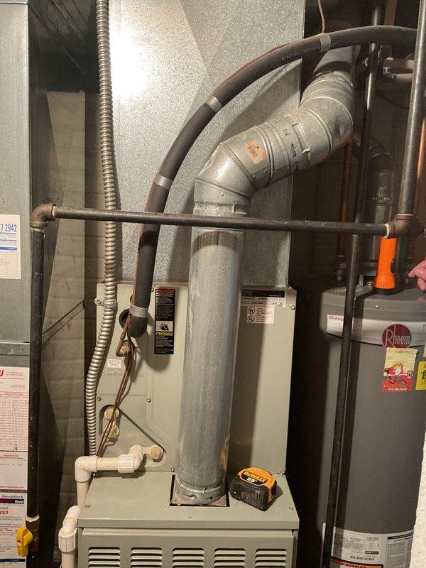 Completed comprehensive estimate for full HVAC system replacement including outdoor condensing unit and indoor furnace. Evaluated existing light blue cylindrical condenser unit located on exterior concrete pad with weathered base and mineral deposits, noting electrical conduit connections and refrigerant line configurations. Assessed indoor furnace unit positioned in utility room alongside water heater, documenting existing ductwork connections, flexible metal conduit runs, and PVC venting system. Photographed equipment specifications, manufacturer labels, and current installation conditions to provide accurate replacement recommendations and ensure proper sizing for new system components.