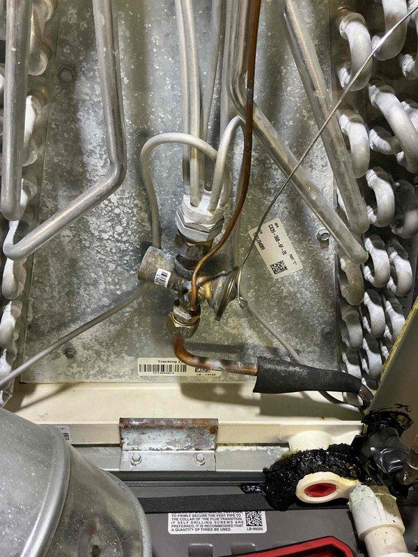 Completed preventive maintenance on 4-year-old air conditioning system. Inspected evaporator coil assembly showing proper A-frame configuration with active condensation indicating normal cooling operation. Verified refrigerant lines, drainage components, and heat exchanger coil condition. All components operating within normal parameters with appropriate moisture accumulation on coil surfaces during cooling cycle.
