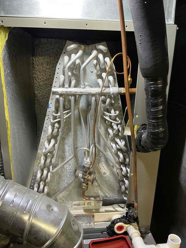 Completed preventive maintenance on 4-year-old air conditioning system. Inspected evaporator coil assembly showing proper A-frame configuration with active condensation indicating normal cooling operation. Verified refrigerant lines, drainage components, and heat exchanger coil condition. All components operating within normal parameters with appropriate moisture accumulation on coil surfaces during cooling cycle.