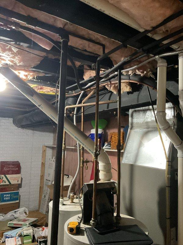 Conducted comprehensive site assessment of existing tanked water heater system in basement utility area to provide estimate for conversion to tankless water heater installation. Evaluated current plumbing infrastructure, including water supply lines, gas connections, venting requirements, and electrical systems necessary for tankless unit operation. Documented existing conditions of mechanical room, noting ceiling-mounted drainage and plumbing lines, exposed joists, ductwork, and available clearances for new equipment installation and code-compliant venting modifications.