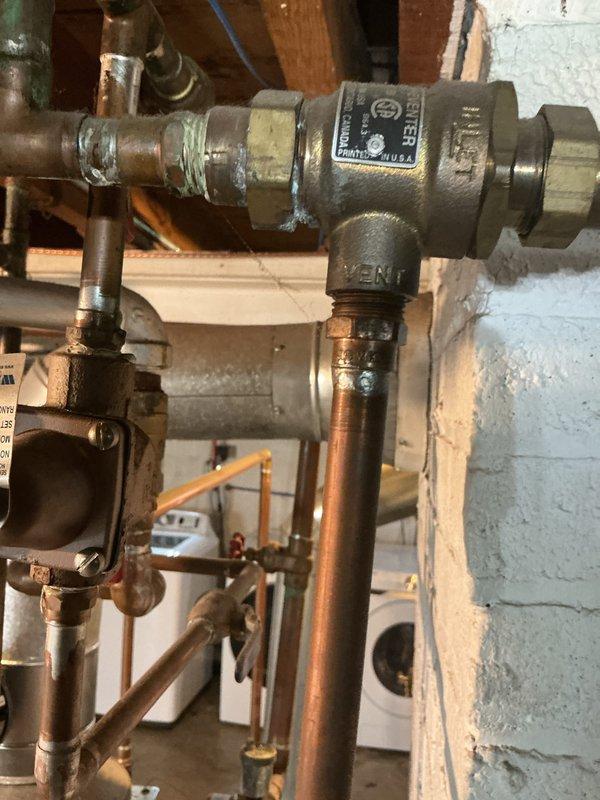 Completed comprehensive inspection of two boilers and two water heaters at the property. Examined all major components including valves, piping connections, air vents, and pressure relief systems. Assessed the condition of Watts brand valve assemblies, copper piping, and brass fittings, noting normal age-related patina and surface oxidation consistent with system operation. Evaluated upstairs thermostat and confirmed non-operational status requiring replacement or repair. Documented all findings with photographs showing plumbing connections, valve assemblies, and associated hardware in basement utility area. All boiler and water heater systems inspected for proper operation, safety compliance, and potential maintenance needs.