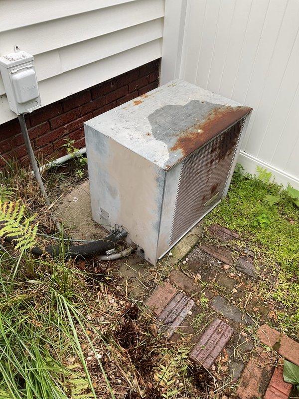 Conducted comprehensive assessment of existing HVAC system for complete replacement. Exterior condenser unit exhibited severe rust deterioration and corrosion throughout metal casing, indicating advanced age and prolonged weather exposure. Unit surrounded by overgrown vegetation and debris accumulation on concrete pad, restricting proper airflow and accelerating component degradation. Interior inspection revealed Lennox furnace system with associated ductwork, air handler components, and standard utility connections. Documented current equipment condition, configuration, and installation parameters through photographic evidence. Provided detailed replacement estimate for new AC system installation including removal of deteriorated outdoor unit, proper site preparation with vegetation clearance, and installation of modern energy-efficient equipment sized appropriately for residential application.