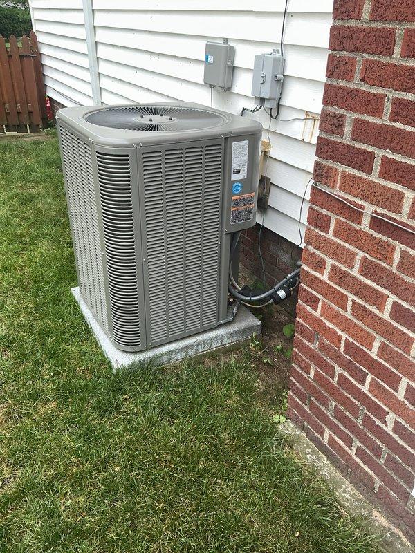 Completed annual MVP cooling maintenance visit on one-year-old residential air conditioning system. Performed comprehensive system inspection including visual assessment of outdoor condensing unit, electrical connections, and refrigerant lines. Unit found operational with accumulated dirt and debris on condenser coils and fins noted during inspection. Documented equipment condition through photographs showing standard residential installation on concrete pad with proper electrical service connections and drainage lines in place.