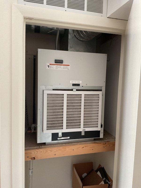Completed estimate for replacement of existing Magic Pak HVAC unit located in interior utility closet. Inspected current installation including unit mounted on wooden platform, associated ductwork, electrical breaker panel, and return air grille. Documented existing equipment configuration, electrical connections, and accessibility via photographs for replacement planning and material specifications.