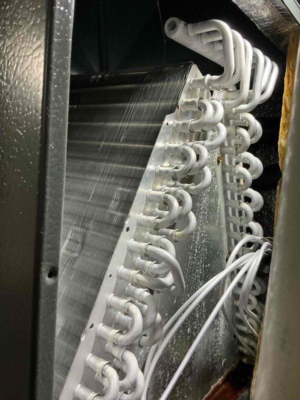 Completed scheduled cooling maintenance on residential HVAC system. Performed comprehensive inspection of evaporator coil assembly and air handler unit, documenting system condition with photographic records. Observed normal condensation on evaporator coil with clean aluminum fins and properly functioning white-coated copper refrigerant tubing in serpentine configuration. Noted moisture accumulation on interior metal surfaces consistent with typical cooling operation. All components operating within normal parameters with no immediate repairs required at this time.