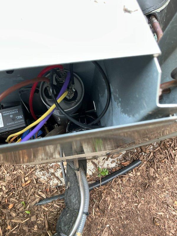 Completed comprehensive preventive maintenance tune-up on outdoor condensing unit less than 10 years old. Inspected and tested dual-run capacitor with multiple wire connections, verified Emerson control module operation, and assessed all electrical connections within the unit housing. Observed moderate rust accumulation on compressor housing and deteriorating foam insulation material, though unit remains operational with all components functioning within normal parameters at time of service.