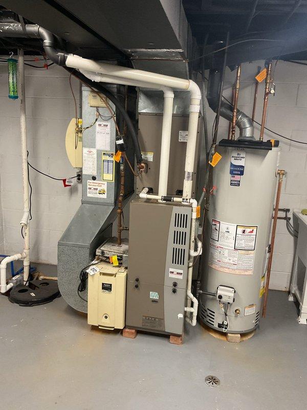 Conducted comprehensive on-site evaluation of existing HVAC system for replacement estimate. Assessed outdoor air conditioning unit positioned on gravel pad with existing electrical conduit and condensate drainage configuration. Inspected indoor furnace and water heater installation in basement mechanical room, noting current ductwork routing, PVC venting system, and equipment layout. Documented existing equipment specifications, clearances, and utility connections to develop accurate replacement proposal for both cooling and heating systems. Photographed current installation conditions including outdoor unit placement, indoor equipment positioning, existing duct connections, and available space for new equipment installation.