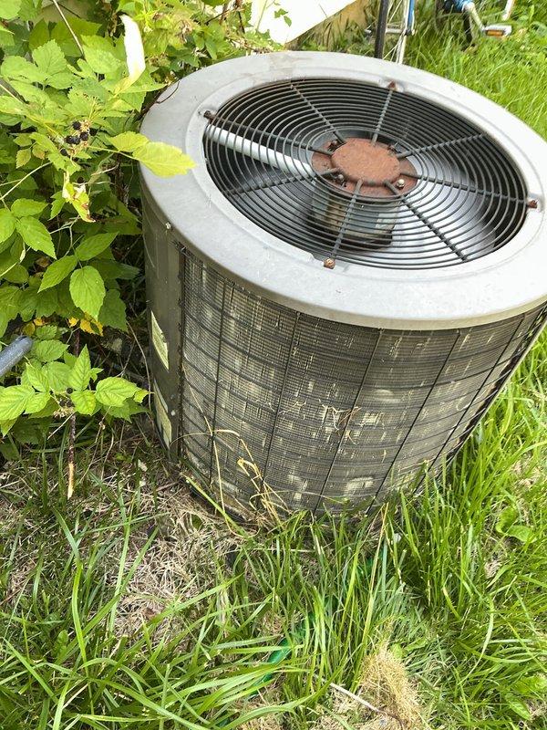 # HVAC Service Report

Responded to no-cooling complaint on residential air conditioning system. Upon arrival, found outdoor condenser unit in overgrown area with significant dirt and debris accumulation on protective grilles and fan assembly. Unit showed signs of extended outdoor exposure with weathering, discoloration, and grime buildup affecting airflow efficiency. Inspected fan motor assembly and noted corrosion on central hub mechanism. Cleared vegetation and debris from around unit perimeter to restore proper airflow clearance. Cleaned condenser coils and protective mesh screening to remove accumulated dirt and organic matter. Tested system operation and verified proper fan rotation and compressor function. Recommended ongoing vegetation management around unit and regular maintenance schedule to prevent future airflow restrictions.
